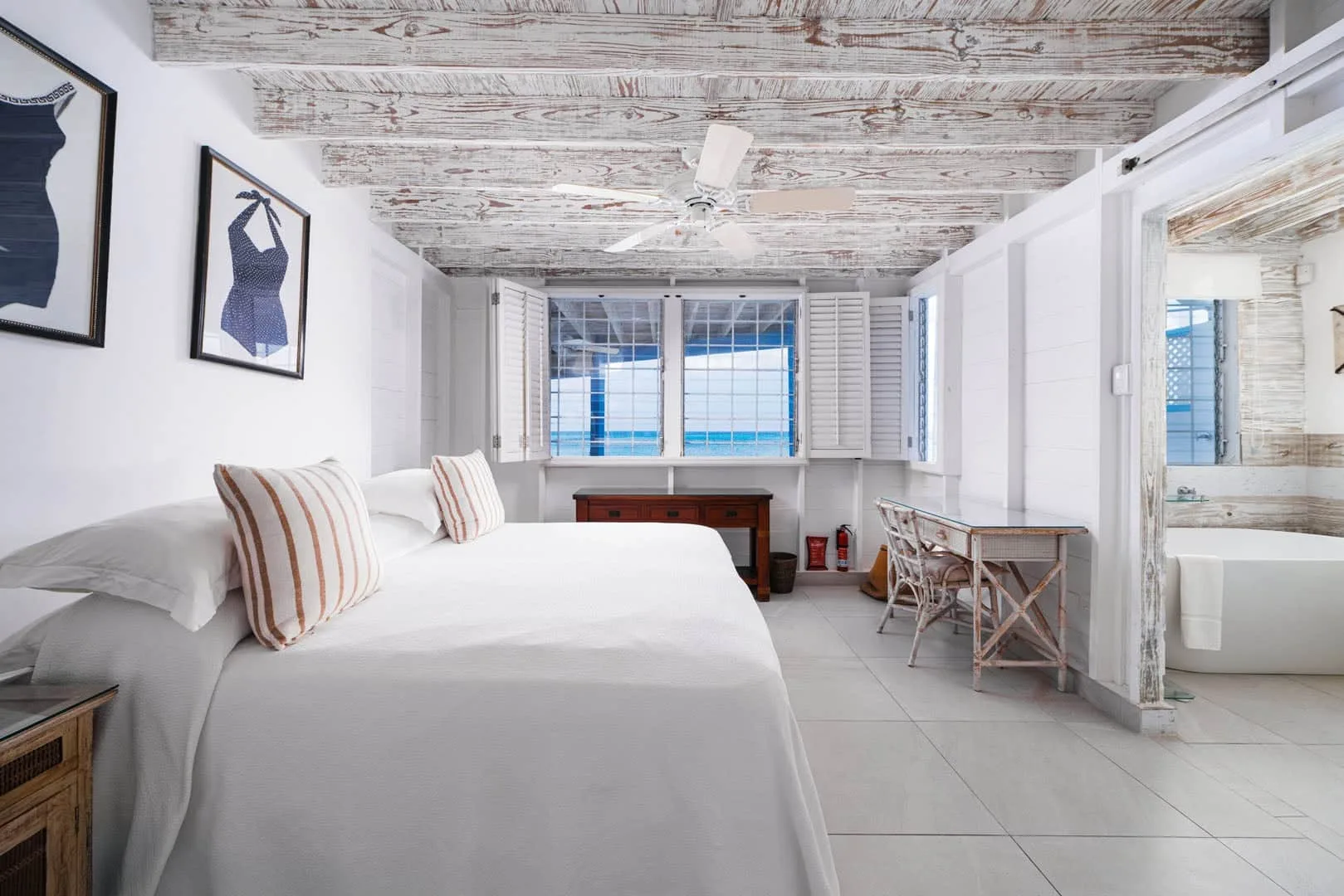 A bright bedroom with a neatly made bed and a desk by the windows.