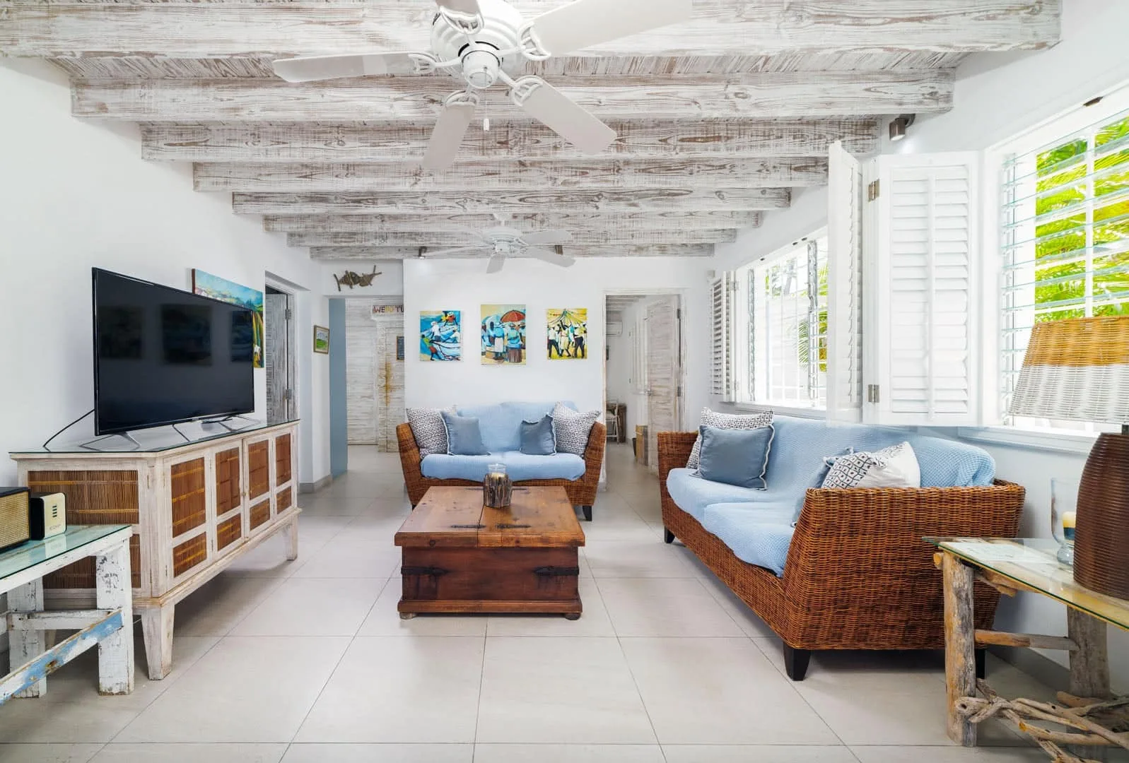 A bright living room with wicker seating, a coffee table, and large windows.