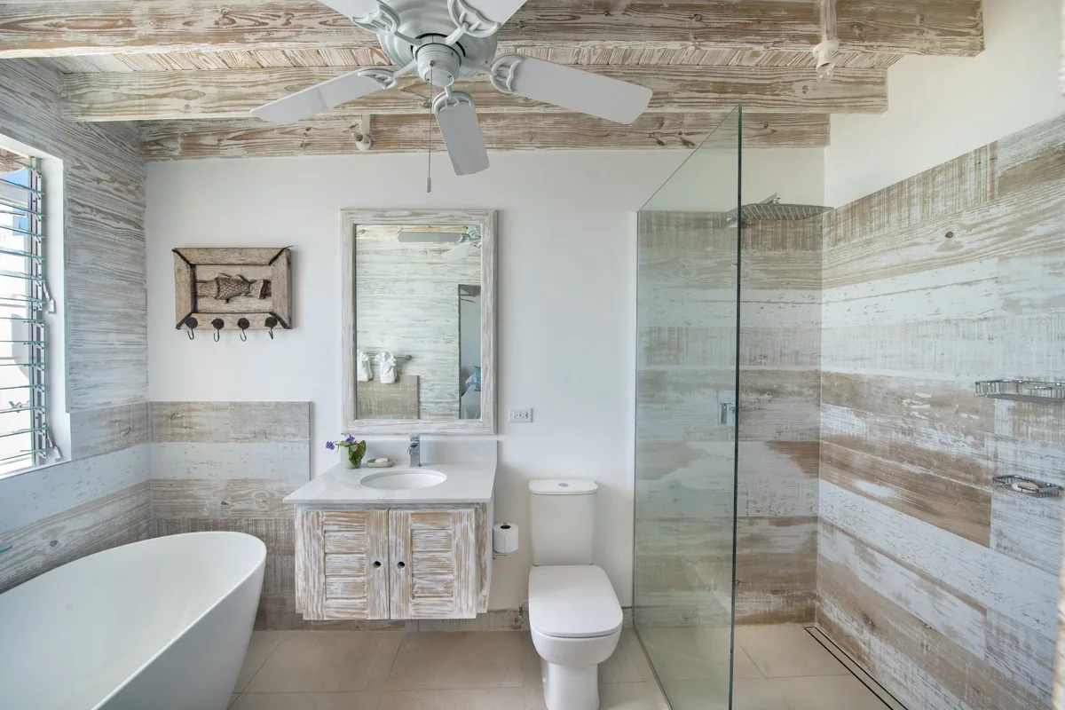 A bright bathroom with a bathtub, vanity, toilet, and glass shower.