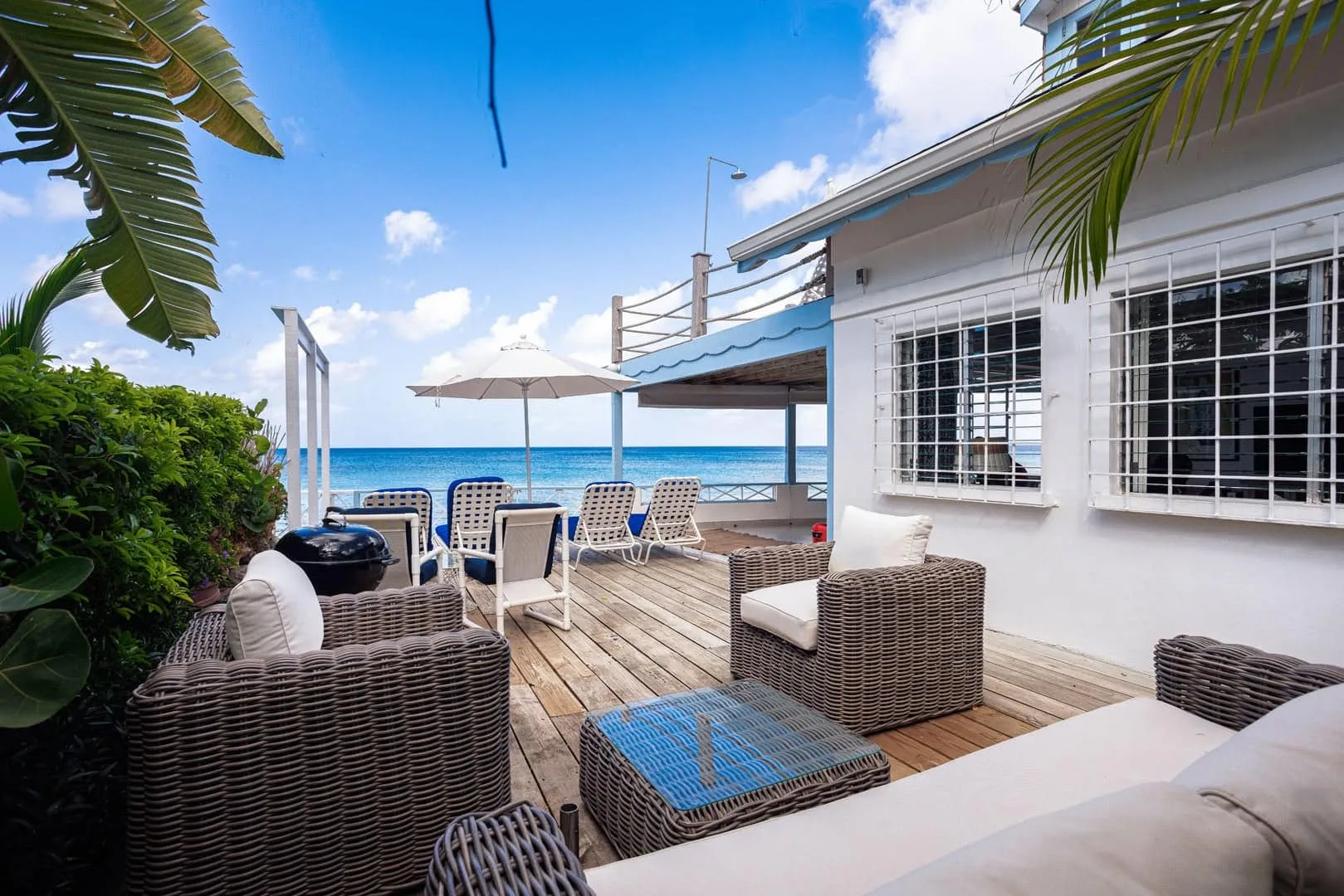 A seaside patio has woven seating and a view of the ocean.