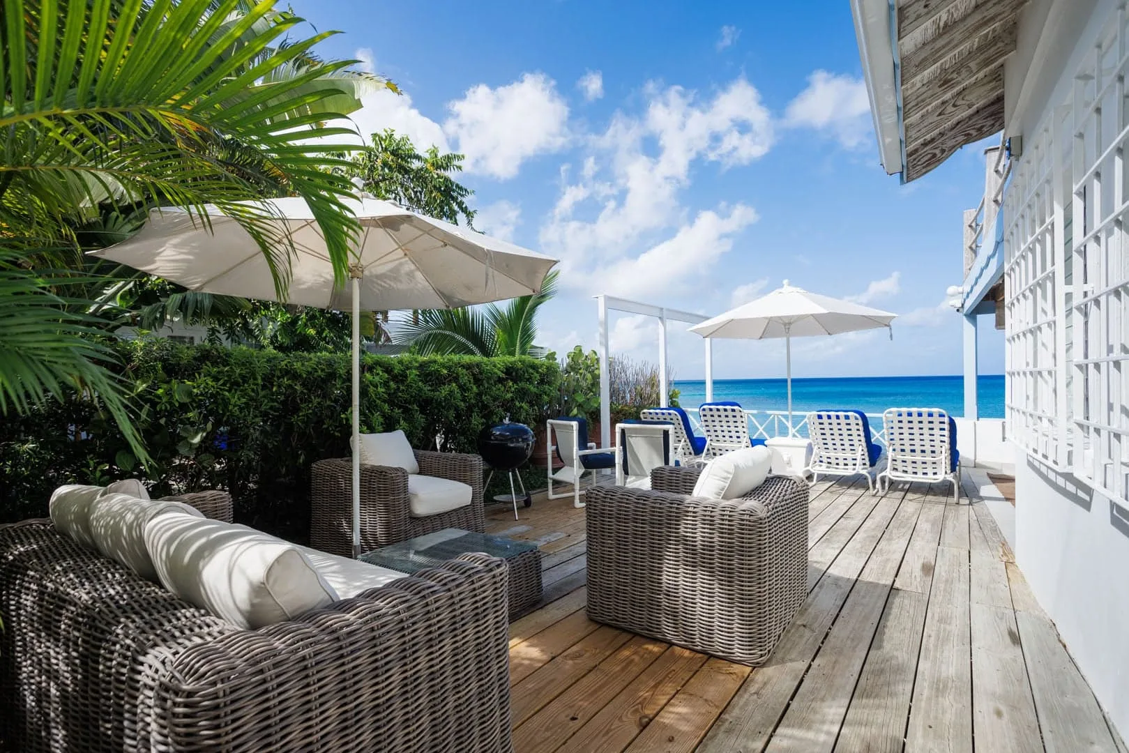 An outdoor deck with seating and umbrellas overlooks the ocean.