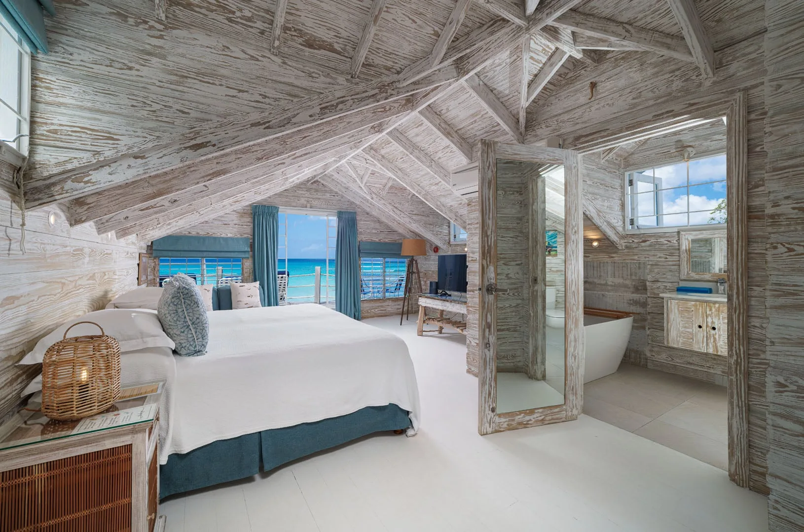 Un dormitorio con una cama grande y vistas al mar a través de puertas de vidrio.