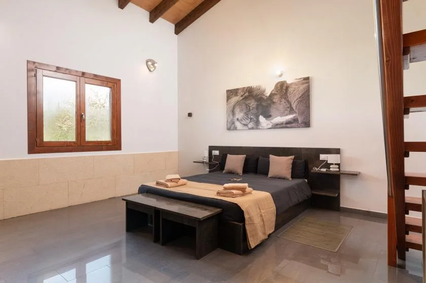 Un dormitorio con una cama oscura, mesitas de noche y una ventana.