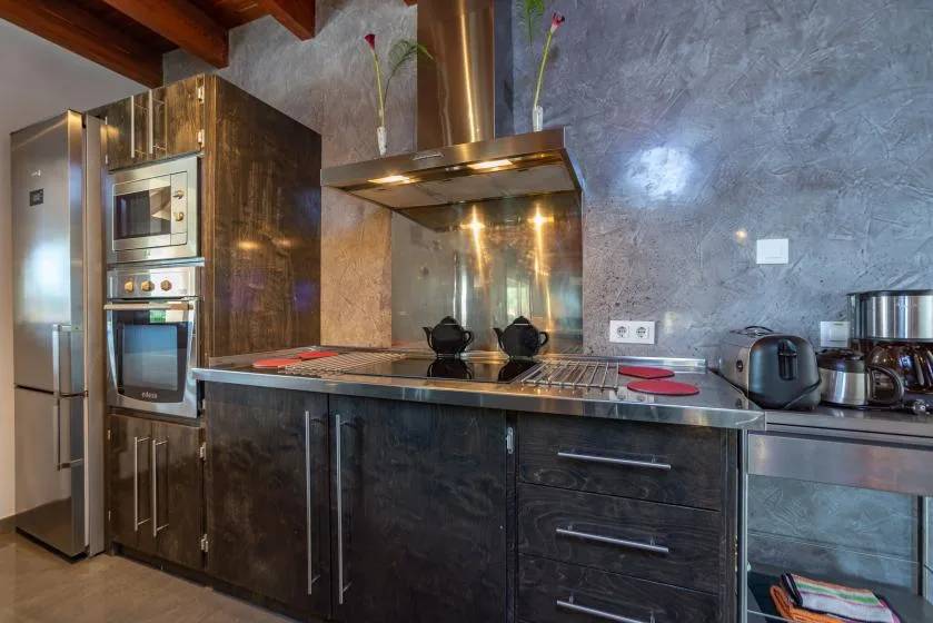 Una cocina moderna con placa de cocina, hornos integrados y armarios oscuros.