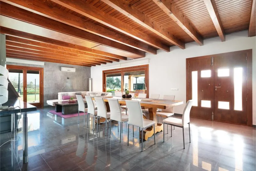 Un comedor con una mesa larga y asientos bajo vigas de madera a la vista.