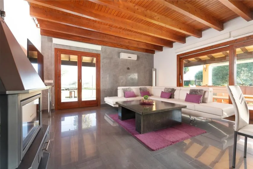 Una sala de estar luminosa con asientos alrededor de una mesa baja bajo vigas de madera.