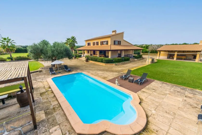 Una piscina al aire libre junto a una casa grande y un césped.