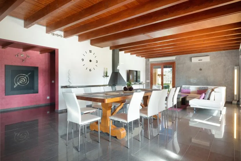 Un espacio abierto de comedor y sala de estar con una mesa larga y asientos blancos.