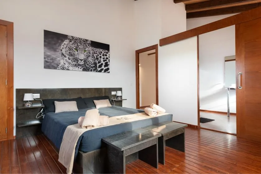 Un dormitorio con una cama, mesas de noche y arte enmarcado en la pared.