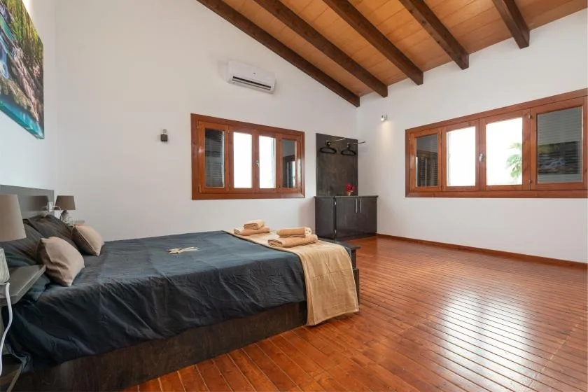 Un dormitorio con una cama bajo vigas de madera expuestas en el techo.