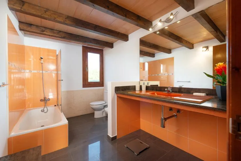 Un baño con ducha de azulejos naranjas, bañera y lavabo.