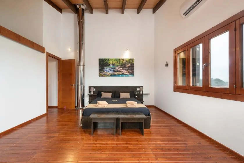 Un dormitorio con una cama bajo vigas vistas y suelo de madera.