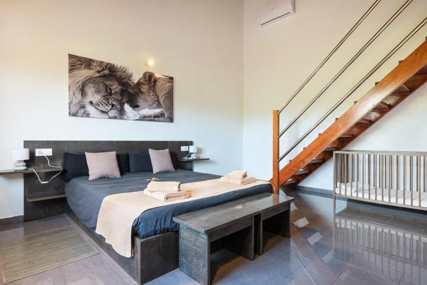 Un dormitorio con una cama y una escalera de madera al lado.
