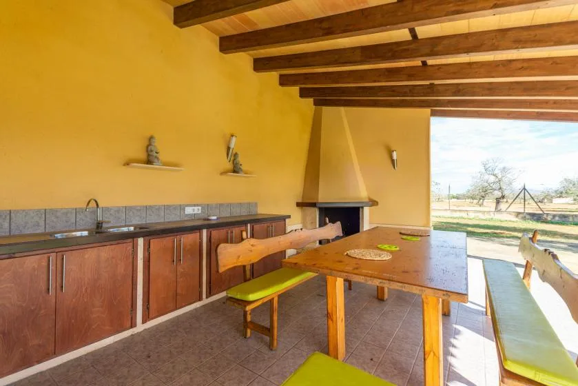 Comedor rústico con una mesa larga de madera junto a una encimera y una chimenea.