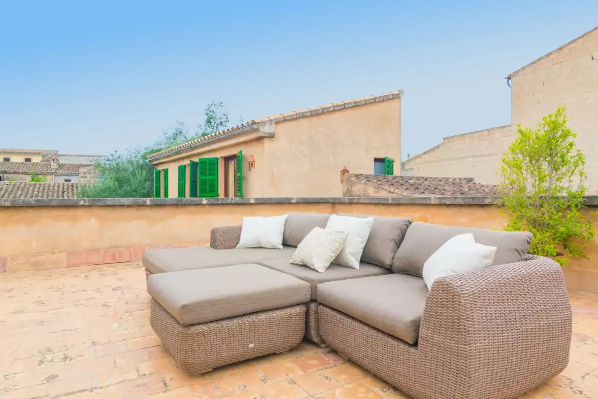 Una terraza en la azotea con una zona de asientos al aire libre y vistas a edificios cercanos.