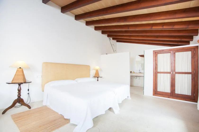 Un dormitorio luminoso con una cama bajo vigas de madera a la vista.