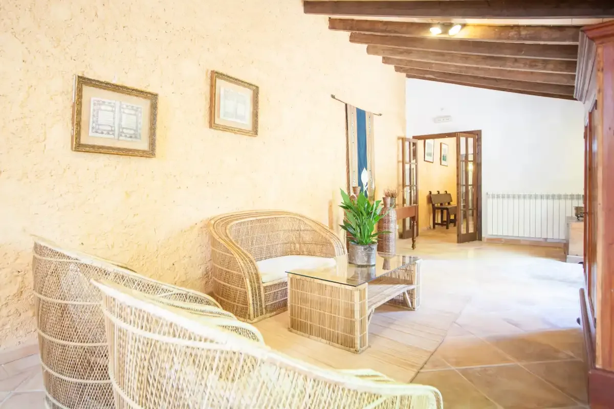 Una luminosa zona de estar interior con asientos tejidos y una mesa pequeña.