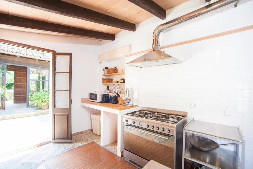 Una cocina luminosa con estufa, encimera y una puerta abierta.