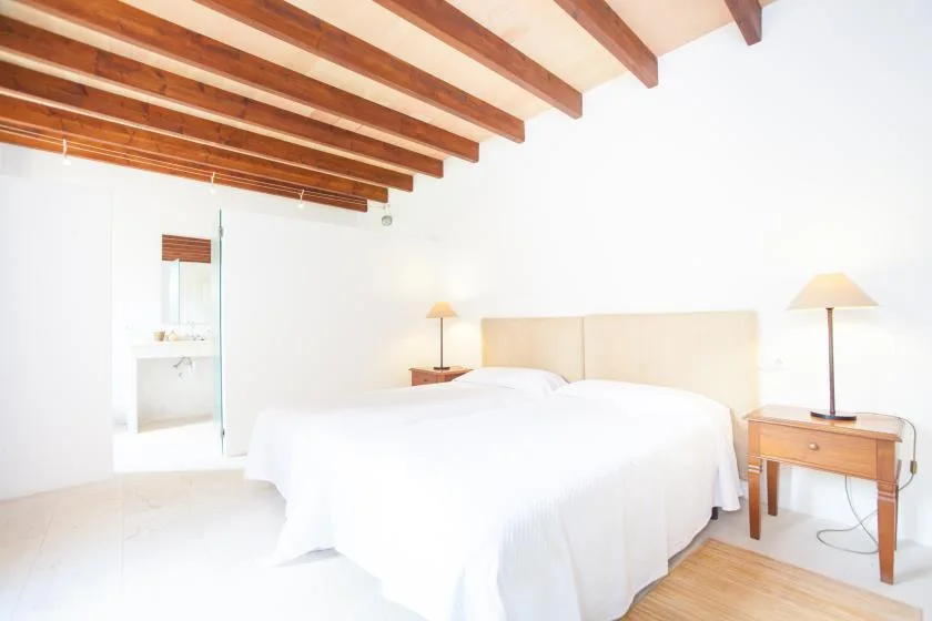 Un dormitorio luminoso con una cama grande bajo vigas de madera expuestas.