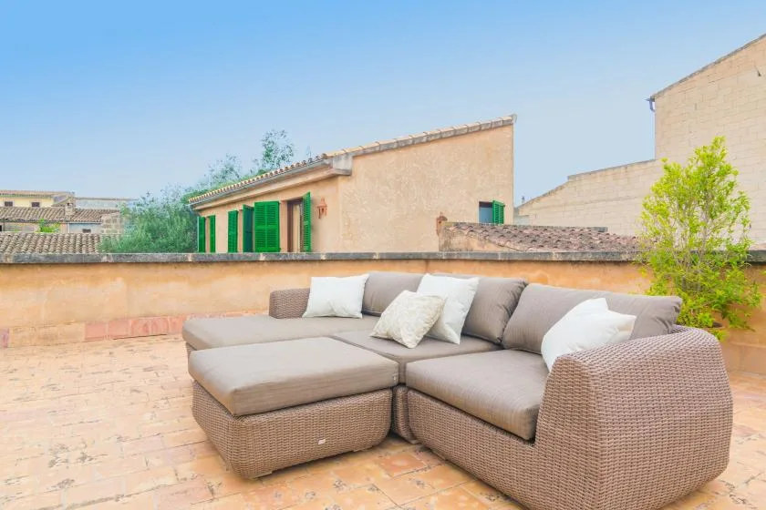 Una zona de estar al aire libre con asientos acolchados en una terraza embaldosada.