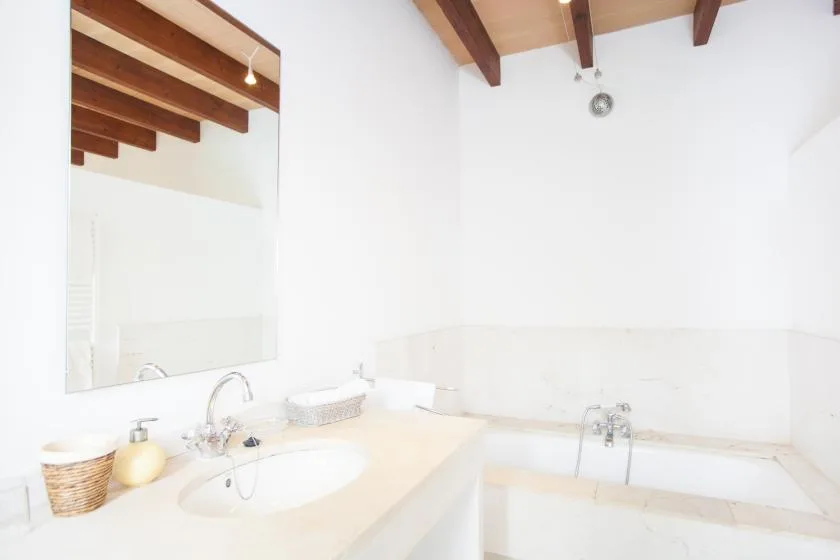 Un baño luminoso con lavabo, espejo y bañera.