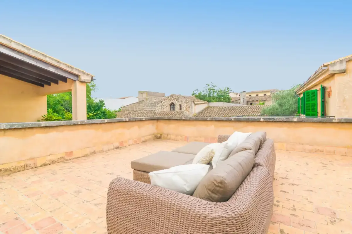 Una terraza en la azotea con asientos acolchados y vistas a edificios cercanos.