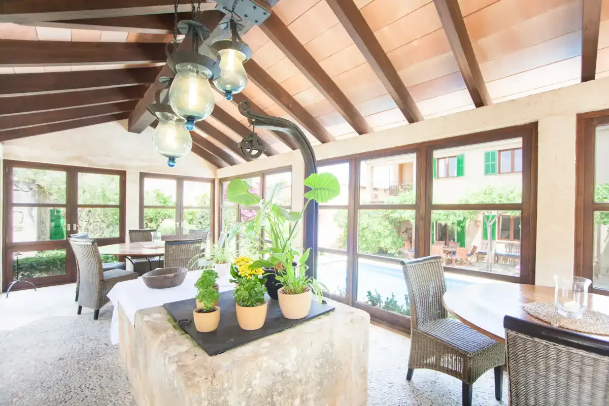 Un comedor luminoso con grandes ventanas y una mesa rodeada de asientos.