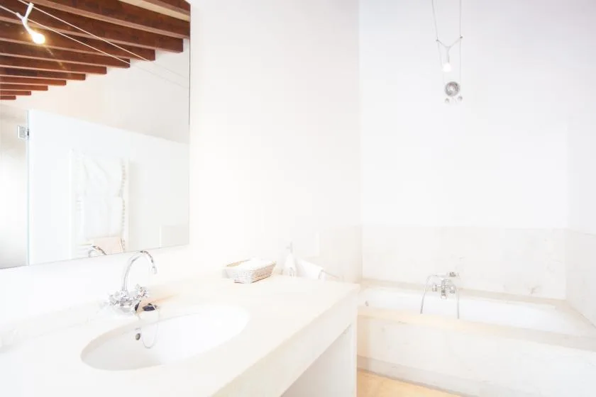 Un baño luminoso con lavabo, espejo y bañera.