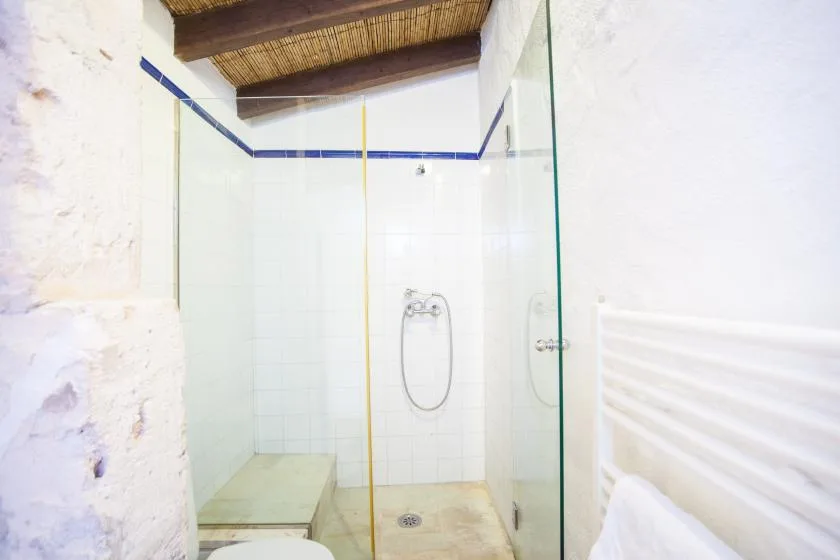 Una zona de ducha con azulejos, paneles de vidrio y una ducha de pared.