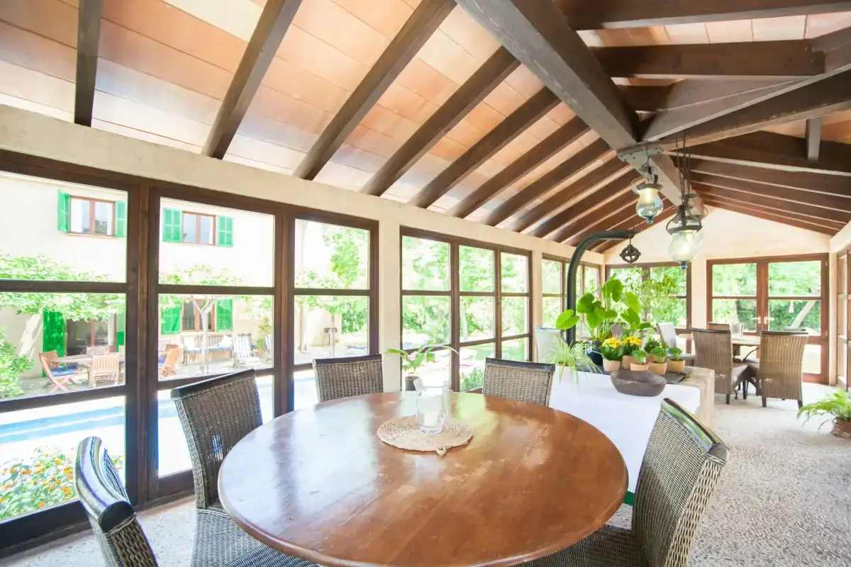 Un comedor luminoso con una mesa redonda de madera junto a grandes ventanas.