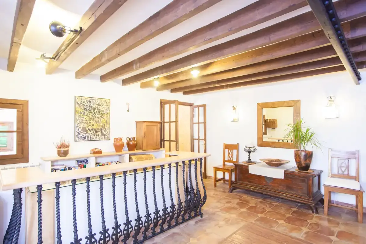 Un rellano interior luminoso presenta vigas de madera expuestas y una barandilla decorativa.
