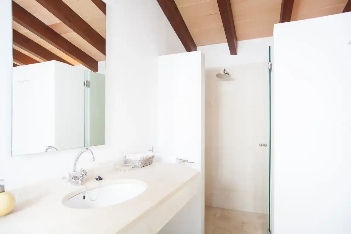 Un baño luminoso con lavabo, espejo y ducha de vidrio.