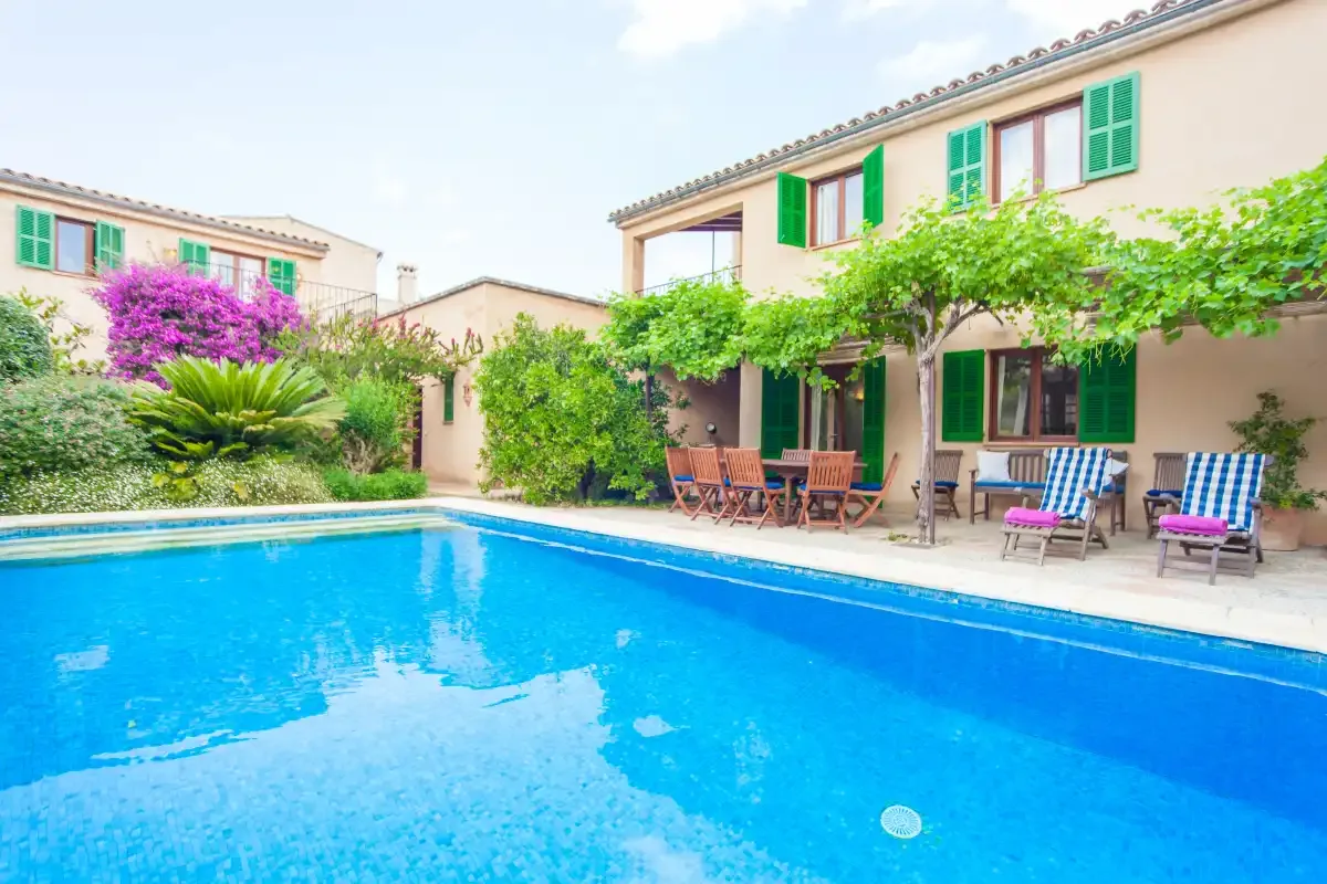 Una piscina frente a un patio cubierto de enredaderas con asientos al aire libre.