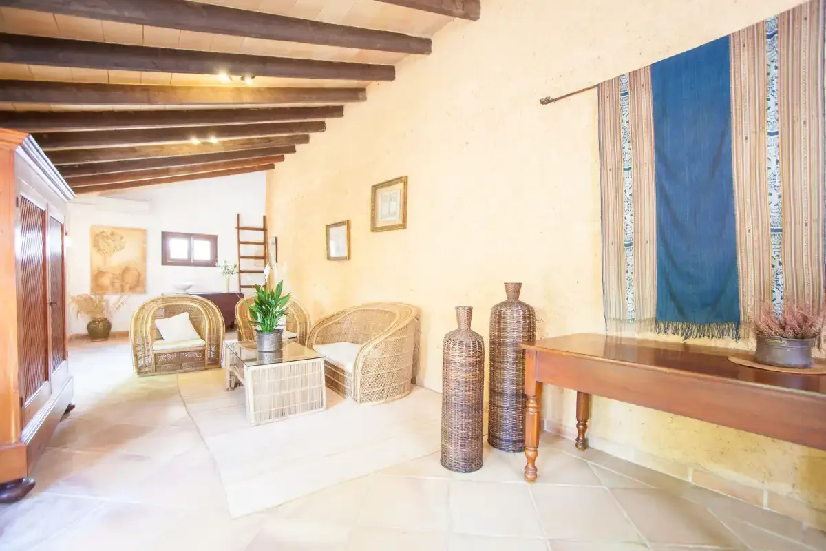Una sala de estar luminosa con asientos de mimbre y una mesa larga de madera.
