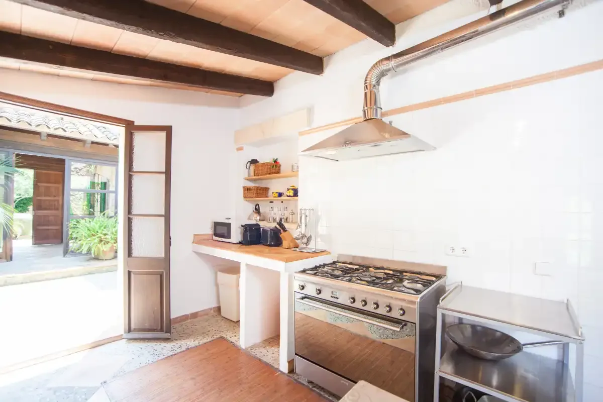 Una cocina luminosa con una estufa y vigas de madera en el techo.