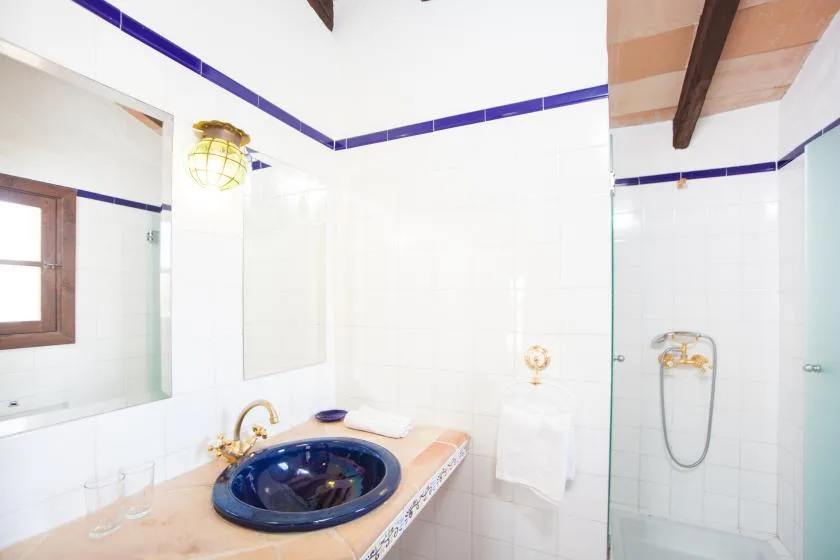 Un baño alicatado con lavabo, espejo de pared y ducha de cristal.