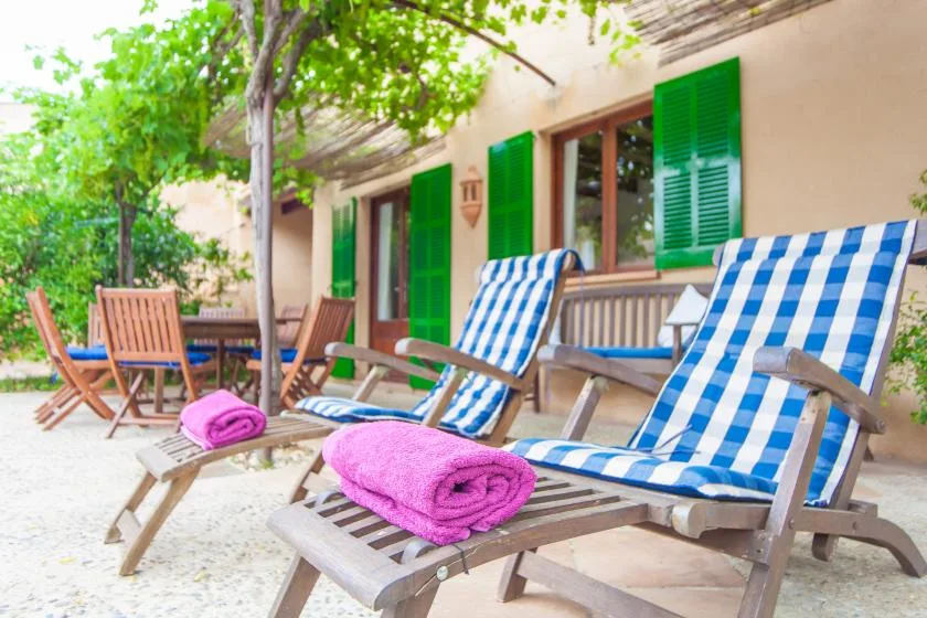 Un patio al aire libre con asientos reclinables y cojines a rayas azules y blancas.
