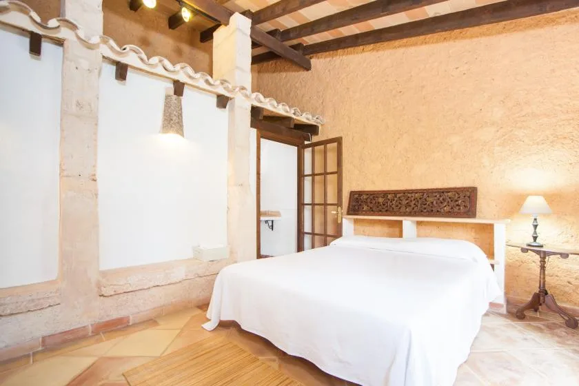 Un dormitorio con una cama doble, vigas de madera expuestas y una lámpara de noche.