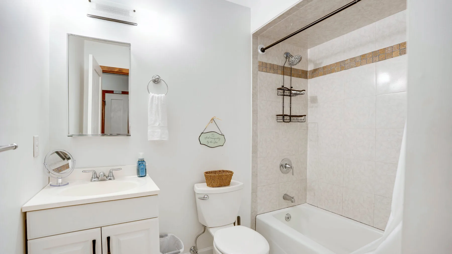 Un baño luminoso con un lavabo junto a una bañera con ducha.