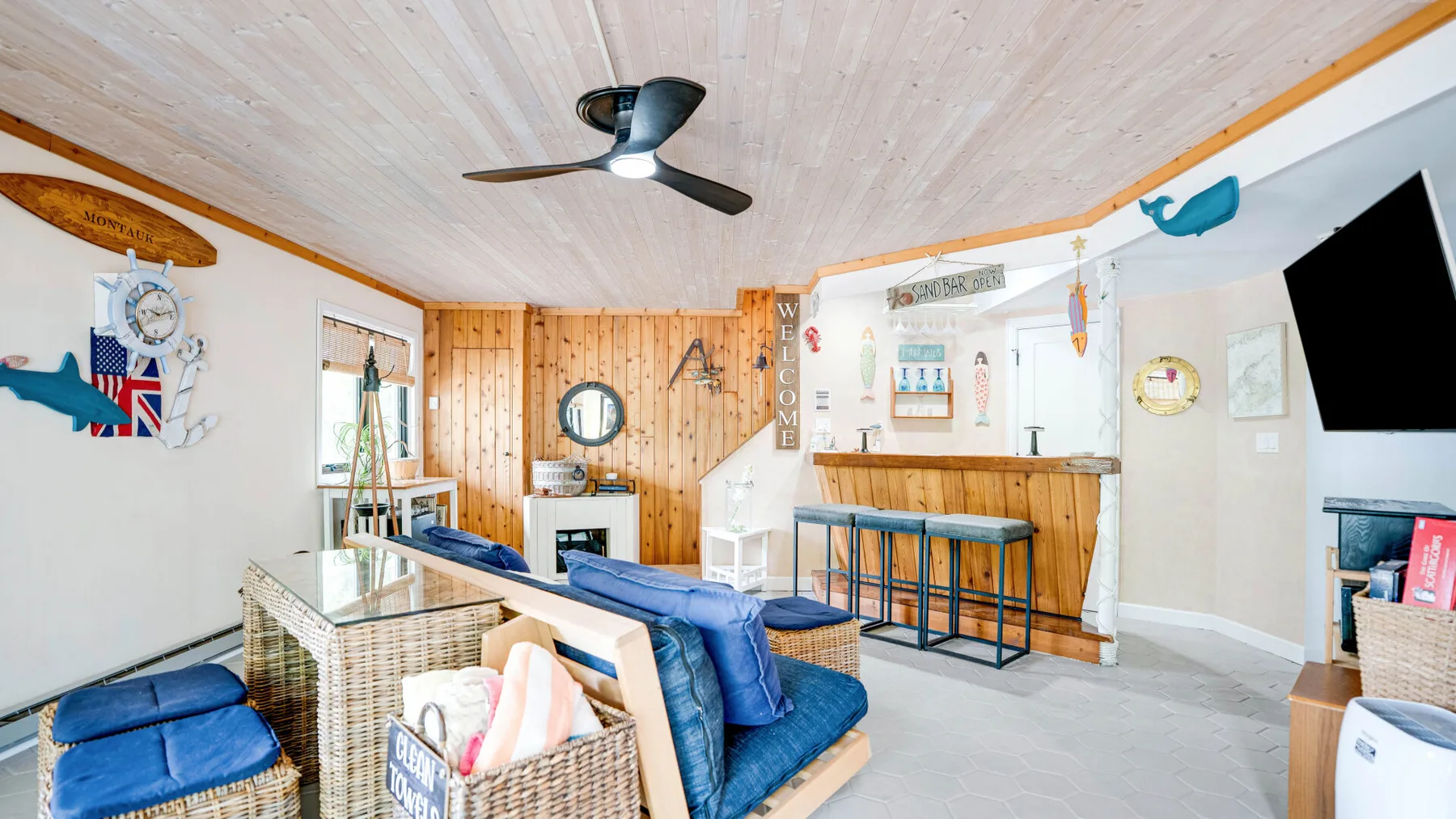 Una sala luminosa con asientos azules, una barra de madera y decoraciones náuticas en las paredes.