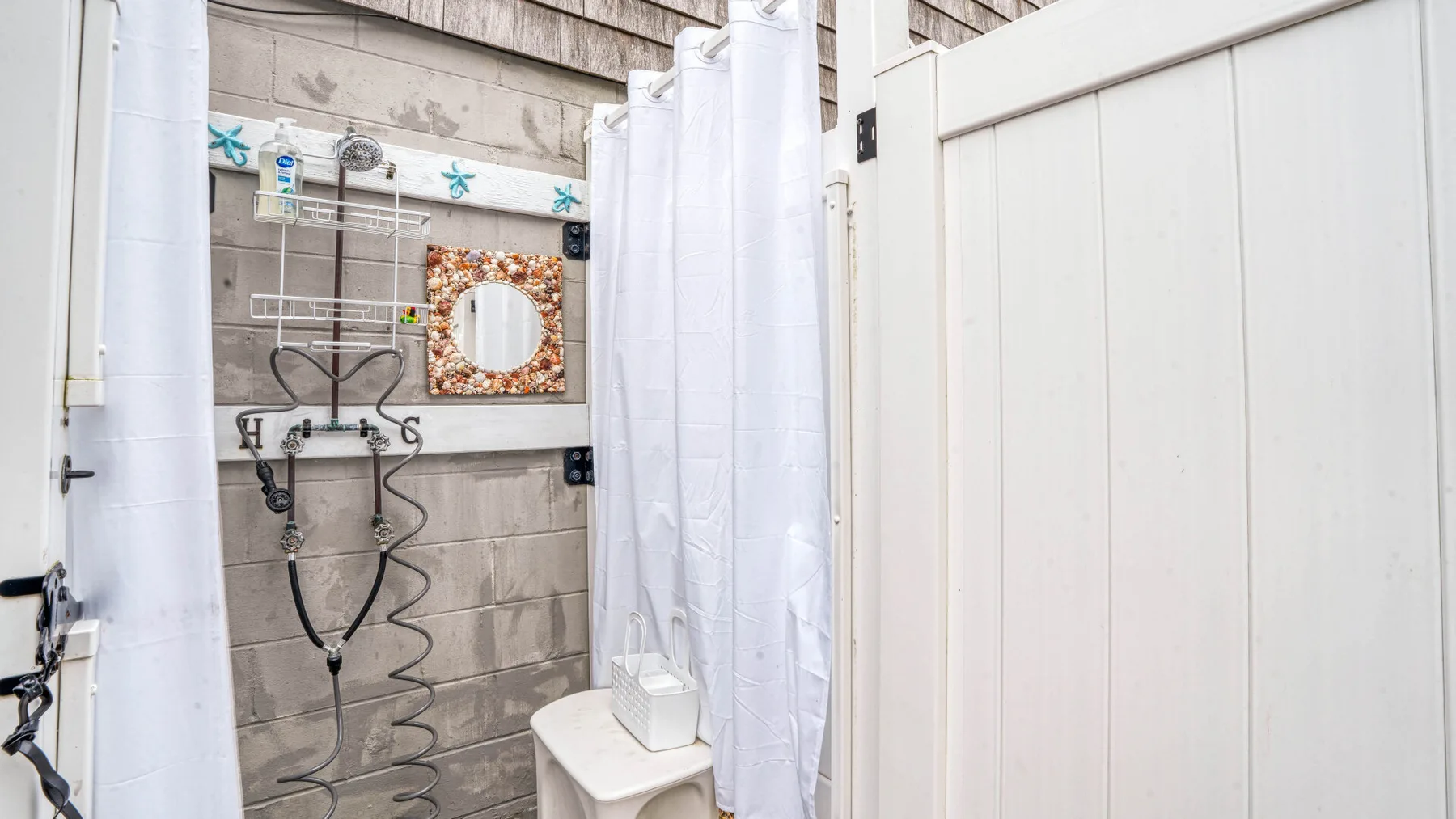 Un baño con cortina de ducha, ducha de pared y lavabo.
