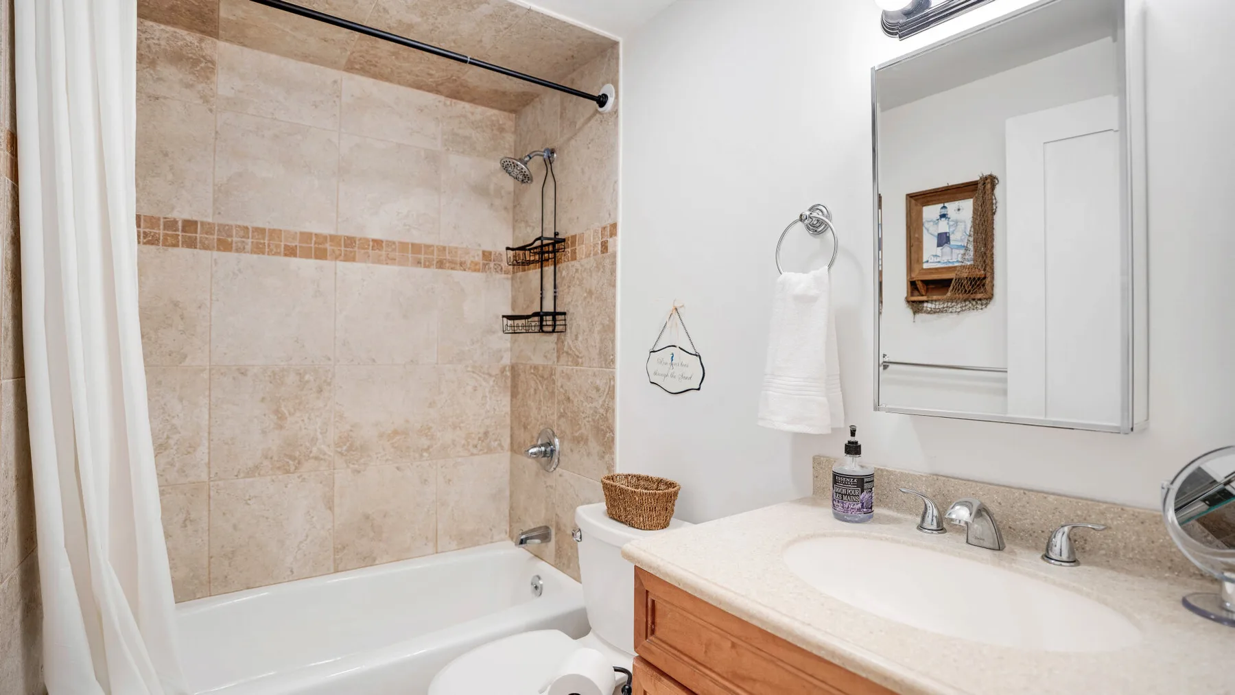 Un baño alicatado con bañera y lavabo bajo un espejo grande.