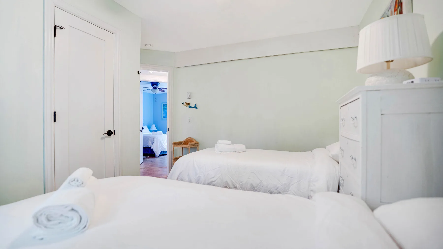 Un dormitorio con dos camas y una cómoda blanca.