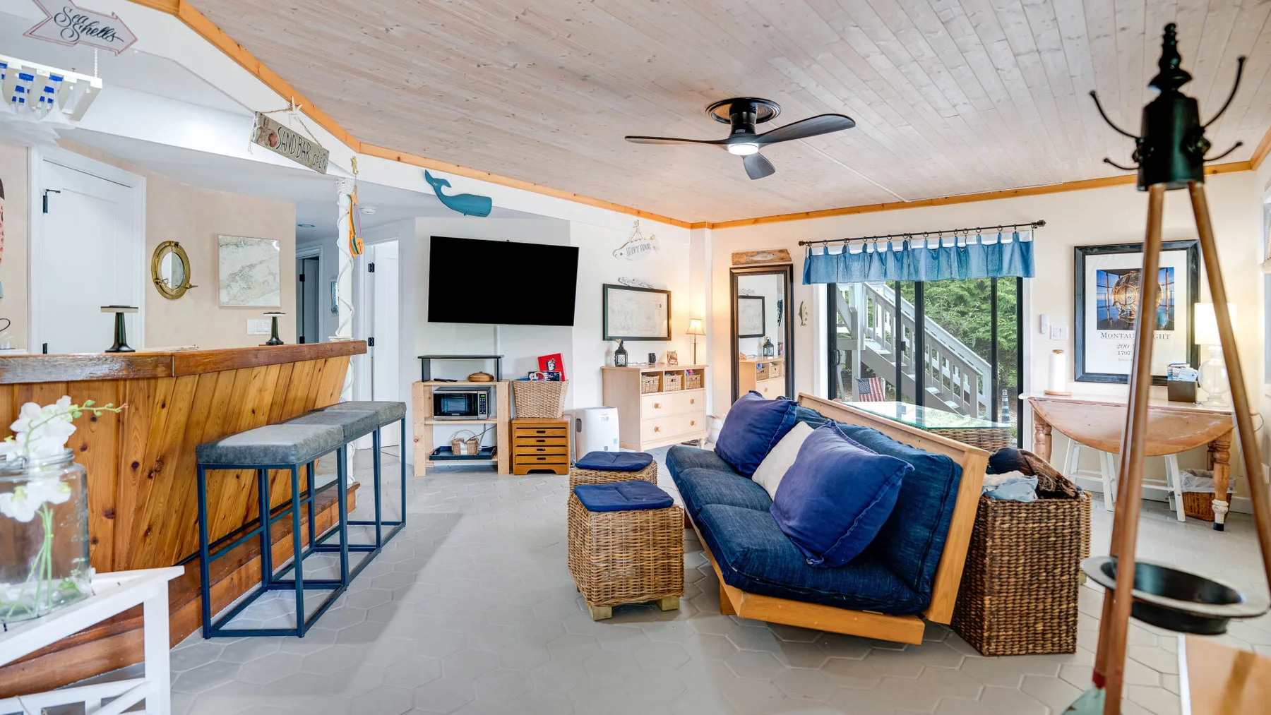 Una sala luminosa con asientos azules, una barra de madera y ventanales.