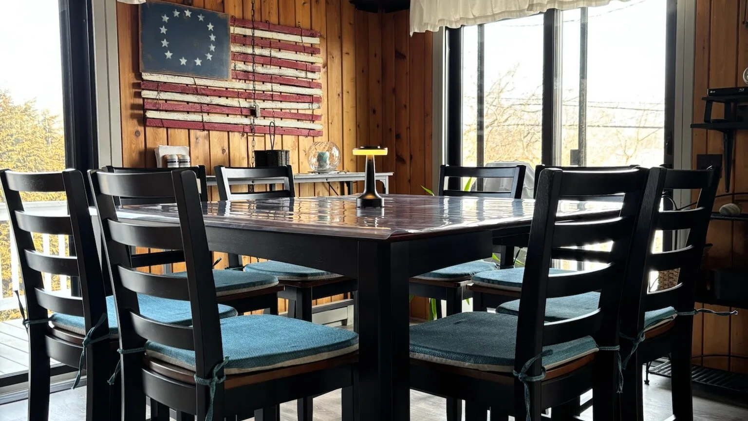 Comedor con una mesa grande y sillas negras junto a ventanales.