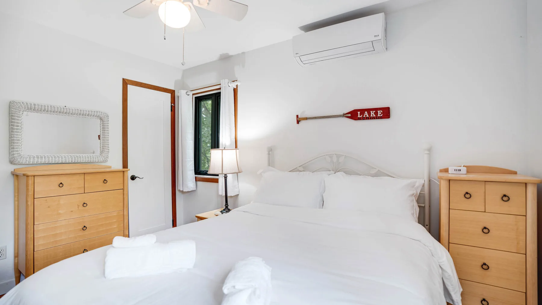 Un dormitorio luminoso con una cama tendida y cómodas de madera a juego.