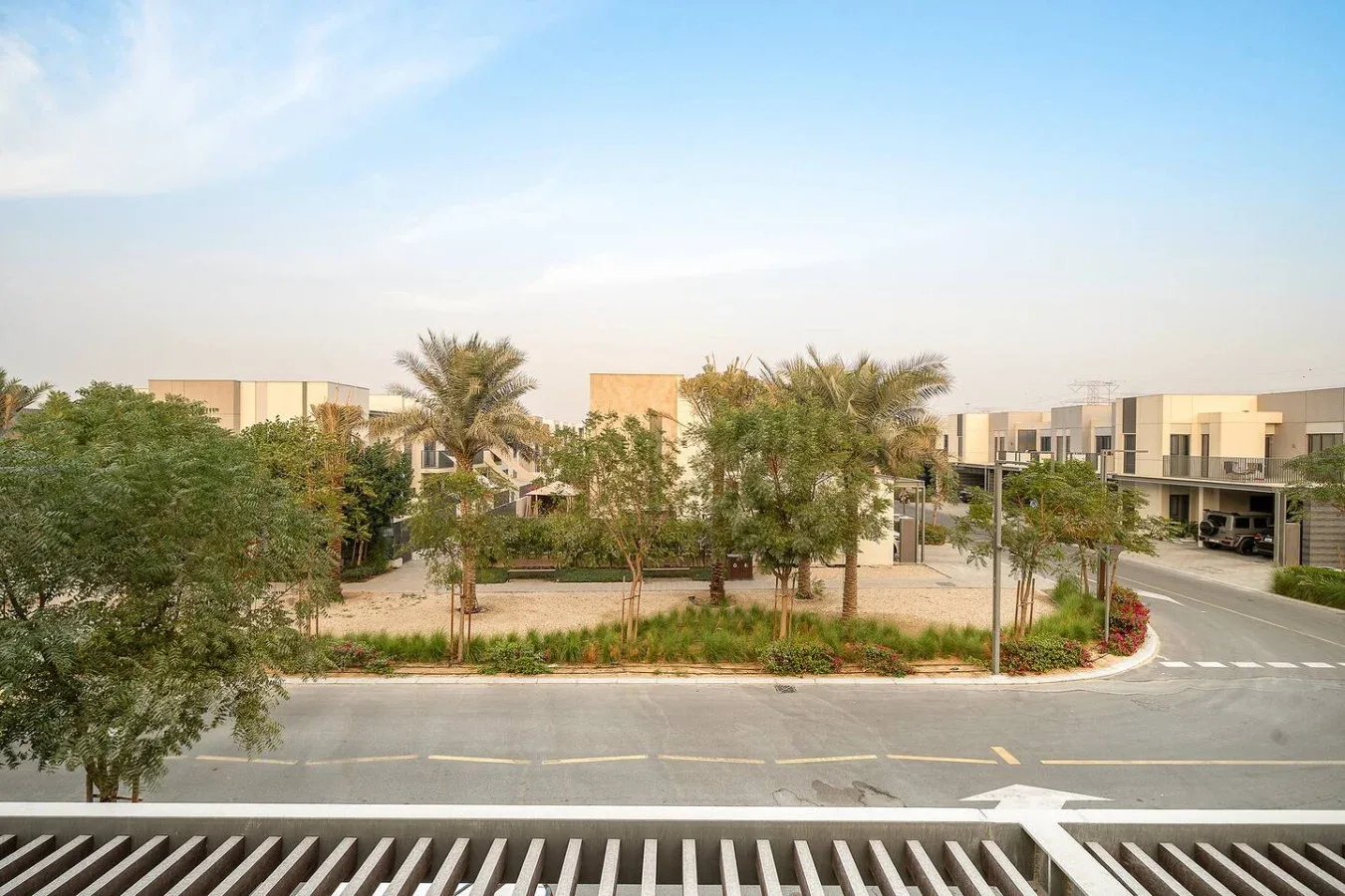 Una calle residencial curva junto a casas modernas, árboles y zonas verdes.