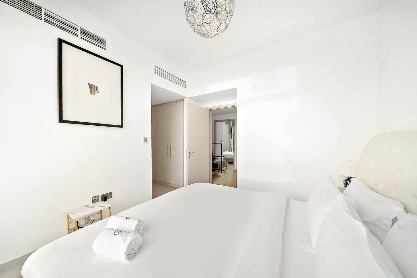 Un dormitorio luminoso con una cama blanca y una puerta abierta.