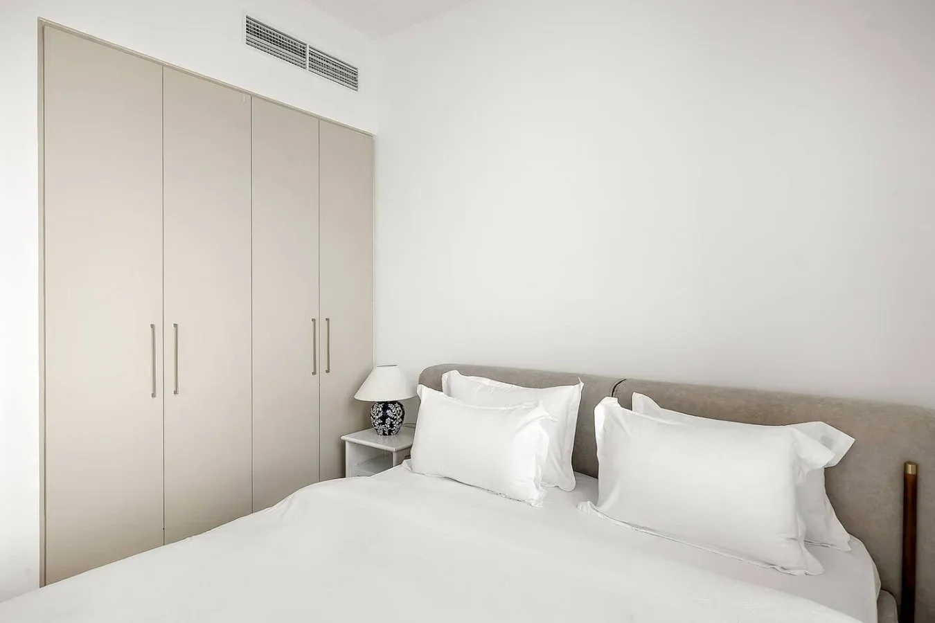 Un dormitorio con una cama bien hecha y un armario alto.