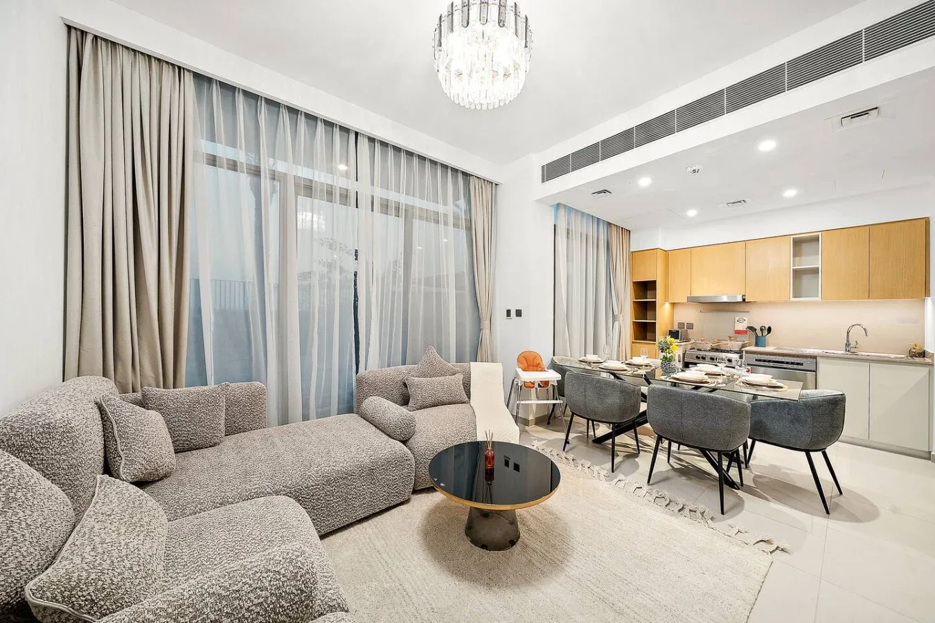 Una sala de estar y cocina abierta con asientos alrededor de una mesa de comedor.